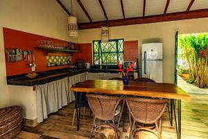 a kitchen with a wooden table and a refrigerator at Casa Papaya in Santa Cruz Cabrália