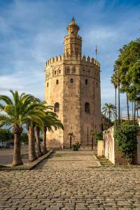 une grande tour en pierre avec des palmiers devant elle dans l'établissement Pierre & Vacances Sevilla, à Séville
