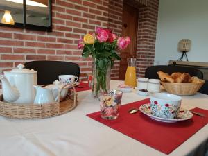 a table with a vase of flowers and pastries on it at Au Charme Di'Sy in Les Cerqueux-de-Maulévrier