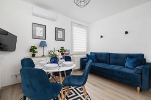 a living room with a blue couch and a table and chairs at Cracow Royal Blue Apartment Avia Estate by Renters in Kraków