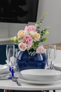 a blue vase with pink flowers in it on a table at Cracow Royal Blue Apartment Avia Estate by Renters in Kraków