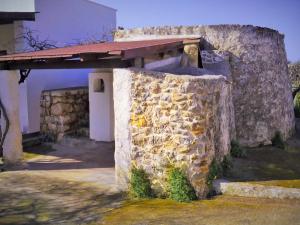 Un muro de piedra al lado de un edificio con techo. en Trullo Don Gabriel, en Alliste
