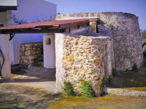 アッリステにあるTrullo Don Gabrielの屋根付きの建物の隣の石壁