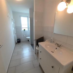 a white bathroom with a sink and a mirror at Ferienwohnung Art in Born in Born