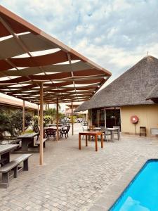 a pavilion with tables and benches and a swimming pool at Hotel Destiny in Ongwediva