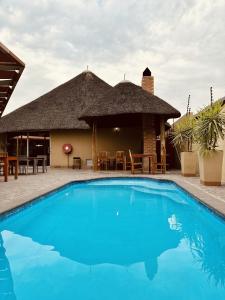 a resort with a large blue swimming pool in front of a building at Hotel Destiny in Ongwediva