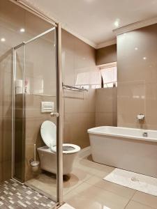 een badkamer met een bad, een toilet en een douche bij Hotel Destiny in Ongwediva