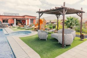 eine Terrasse mit Stühlen und einem Sonnenschirm neben einem Pool in der Unterkunft Shangri-La Fuerteventura in Tefía