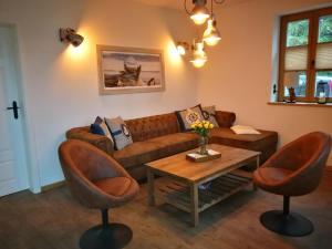 salon z brązową kanapą i 2 krzesłami w obiekcie Boddenkutter w mieście Born