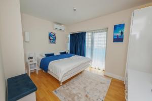 a white bedroom with a bed and a window at ORBI CITY SUITE in Batumi