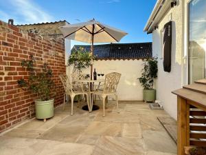 uma mesa e cadeiras com um guarda-sol num pátio em Pilchard Cottage em Dawlish