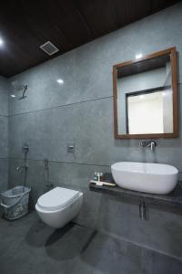 a bathroom with a sink and a toilet and a mirror at Hotel Triton - Near US Embassy in Mumbai