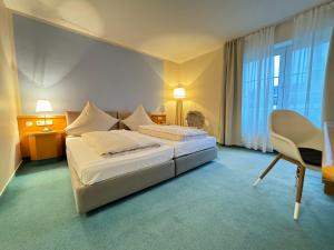 Pokój hotelowy z 2 łóżkami i krzesłem w obiekcie Privathotel Bremer w mieście Bergisch Gladbach