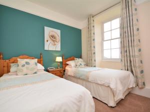 2 camas en un dormitorio con paredes azules y ventana en 2 Bed in St Austell TVISS, en Pentewan