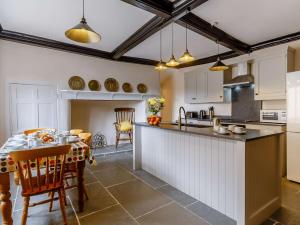 a kitchen with white cabinets and a table with chairs at 3 Bed in Charmouth 89004 in Wootton Fitzpaine