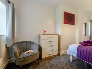 a bedroom with a chair and a dresser next to a bed at 3 Bed in Pooley Bridge 89068 in Tirril