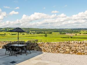 a patio with a table and chairs and a stone wall at 3 Bed in Pooley Bridge 89068 in Tirril