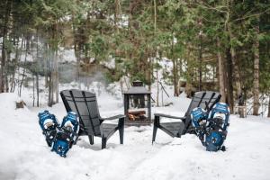 four chairs in the snow next to a fire at Cabines Niksen in Saint Adolphe D'Howard