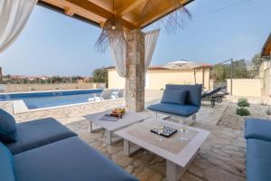 a patio with blue furniture and a swimming pool at Villa Kalista Istriana in Mednjan