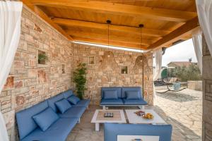 a patio with blue couches and a stone wall at Villa Kalista Istriana in Mednjan