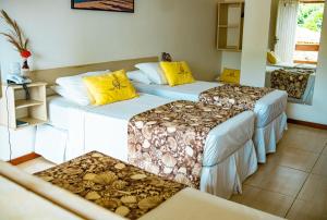 3 camas en una habitación con almohadas amarillas en Pousada Portal da Concha, en Itacaré
