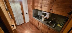 eine kleine Küche mit einer Spüle und einer Mikrowelle in der Unterkunft COURMAYEUR, VERRAND: IMMERSA NEL VERDE E CON VISTA in Verrand