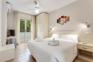 a bedroom with a large white bed with two towels at Hotel Cuba in Milano Marittima