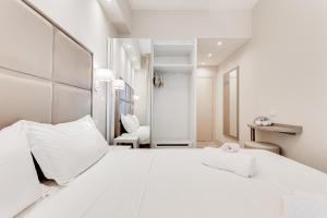 a white bedroom with a white bed and a chair at Hotel Cuba in Milano Marittima