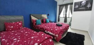 a bedroom with two beds with red sheets and blue walls at Mawar Casa Homestay Kluang in Kluang