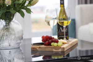 a table with two glasses of white wine and grapes at Poole Quay, elegant apt, sleeps 4, Wi-Fi & parking - Carters Quay View in Poole