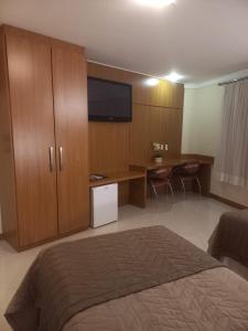 a bedroom with a bed and a desk with a television at Barbur Center Hotel in Ponta Grossa