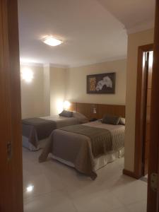 two beds in a hotel room with two beds at Barbur Center Hotel in Ponta Grossa