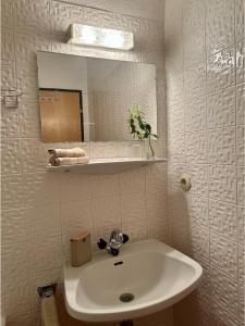 Baño blanco con lavabo y espejo en Apartment A'Horn, en Sankt Johann in Tirol