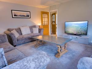 a living room with a table and a flat screen tv at Braeside - Family home in Nethy Bridge in Nethy Bridge