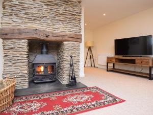 a living room with a stone fireplace and a television at 4 Bed in Berrynarbor 43640 in Berrynarbor