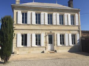 ein altes weißes Haus mit einem Baum davor in der Unterkunft La Chartreuse des Vignes in Ludon-Médoc