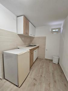 uma cozinha vazia com um lavatório e um frigorífico em Apartmani Radman em Igalo