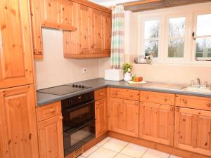 的住宿－2 Bed in Cirencester CC094，厨房配有木制橱柜和炉灶烤箱。