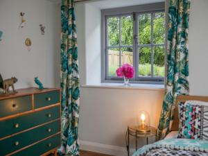 2 Bed in High Bickington 49558 في High Bickington: غرفة نوم مع نافذة و مزهرية مع الزهور الزهرية