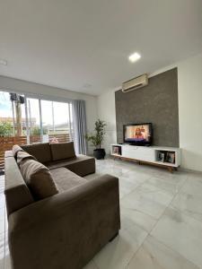 ein Wohnzimmer mit einem Sofa und einem Flachbild-TV in der Unterkunft Casa com Piscina em Xangri-Lá RS in Xangri-lá