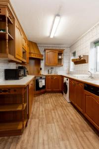 uma cozinha com armários de madeira e uma máquina de lavar e secar roupa em 3BR Cottage in the Heart of Cheadle em Baguley