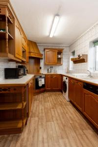 cocina con armarios de madera, lavadora y secadora en 3BR Cottage in the Heart of Cheadle en Baguley