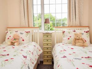 2 ours en peluche assis sur 2 lits dans une chambre dans l'établissement 2 Bed in Padstow 51925, à Egloshayle