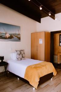 a bedroom with a bed and a wooden cabinet at DESERT DREAMS B&B in Walvis Bay