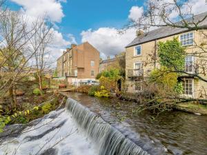 a river with a waterfall in front of buildings at 3 Bed in Hayfield 54472 in Hayfield
