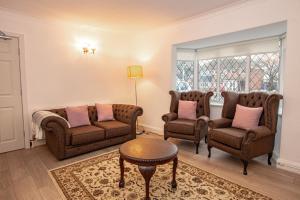 a living room with two chairs and a table at 3BR Cottage in the Heart of Cheadle in Baguley