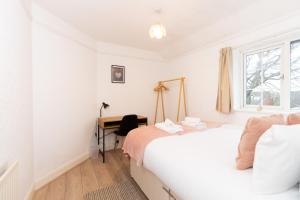 um quarto com uma cama, uma secretária e uma janela em 3BR Cottage in the Heart of Cheadle em Baguley