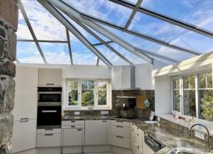 a kitchen with white cabinets and a glass roof at Bremenvoir Barn in Bunessan