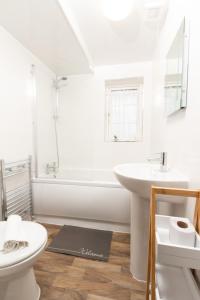 La salle de bains est pourvue d'un lavabo, d'une baignoire et de toilettes. dans l'établissement 3BR Cottage in the Heart of Cheadle, à Baguley