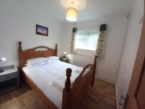 a bedroom with a wooden bed and a window at Penglais Lodge in Aberystwyth